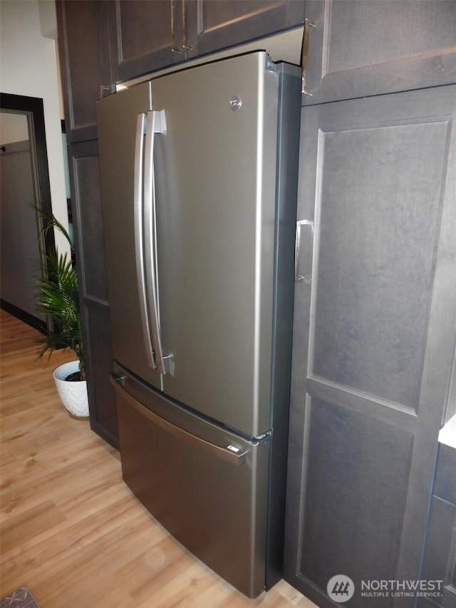 room details with dark brown cabinetry, freestanding refrigerator, and light wood-style floors