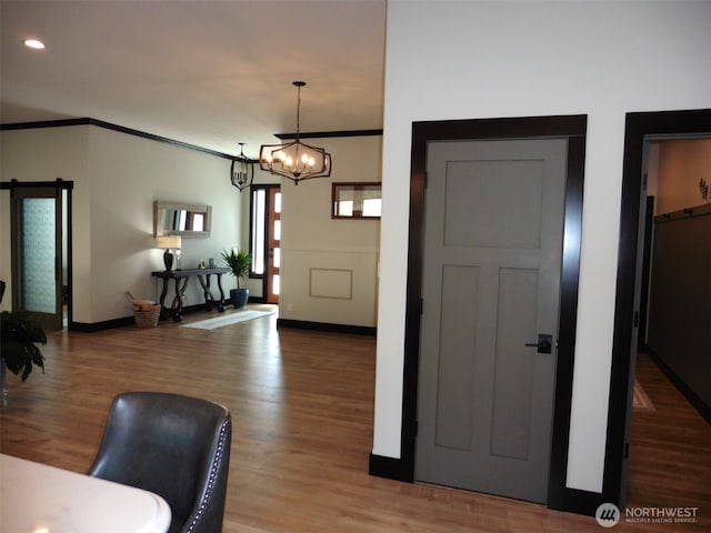 foyer entrance with wood finished floors, baseboards, an inviting chandelier, recessed lighting, and ornamental molding