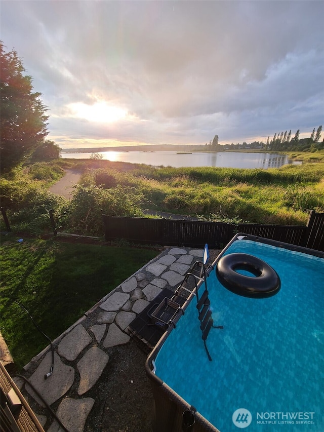 view of pool featuring fence and a water view