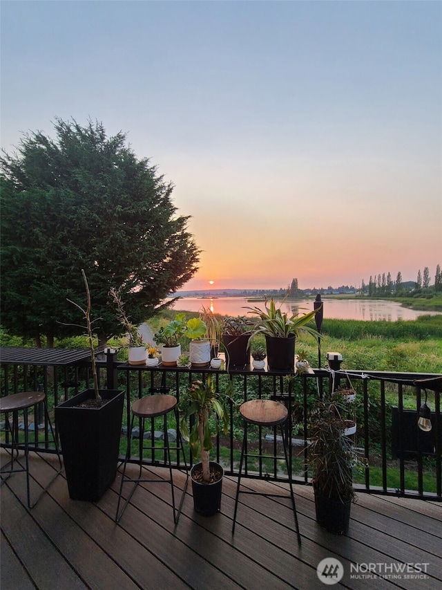 deck at dusk featuring a water view