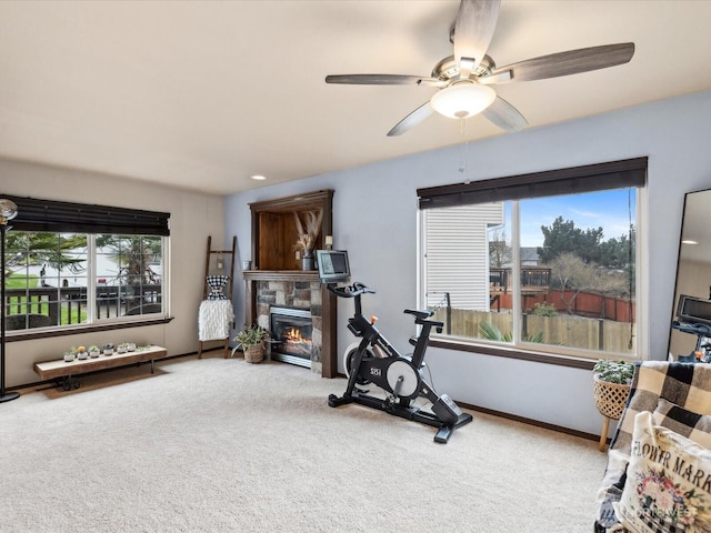 workout room featuring baseboards, carpet floors, ceiling fan, and a fireplace