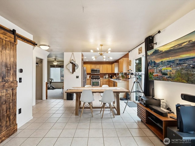 kitchen with light tile patterned floors, light brown cabinets, appliances with stainless steel finishes, and a barn door