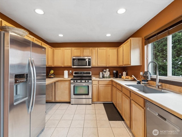 kitchen with light tile patterned floors, a sink, light brown cabinetry, light countertops, and stainless steel appliances