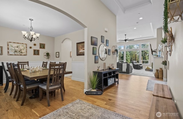 dining room featuring ceiling fan with notable chandelier, wood finished floors, recessed lighting, arched walkways, and baseboards