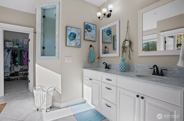 full bath with double vanity, a spacious closet, tasteful backsplash, and a sink