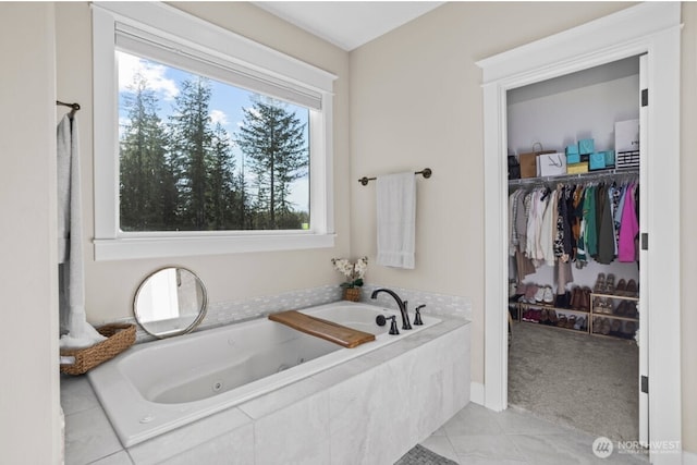 full bath with tile patterned flooring, a spacious closet, and a whirlpool tub