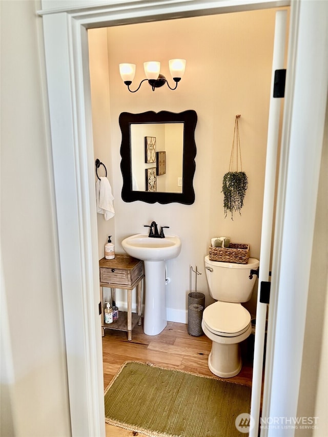 bathroom with toilet, wood finished floors, and baseboards