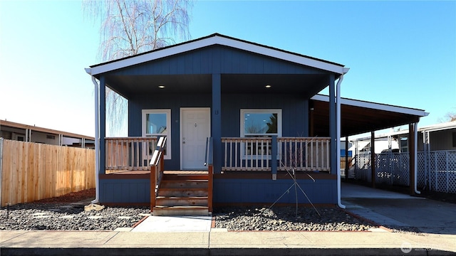 manufactured / mobile home featuring an attached carport, a porch, fence, and driveway