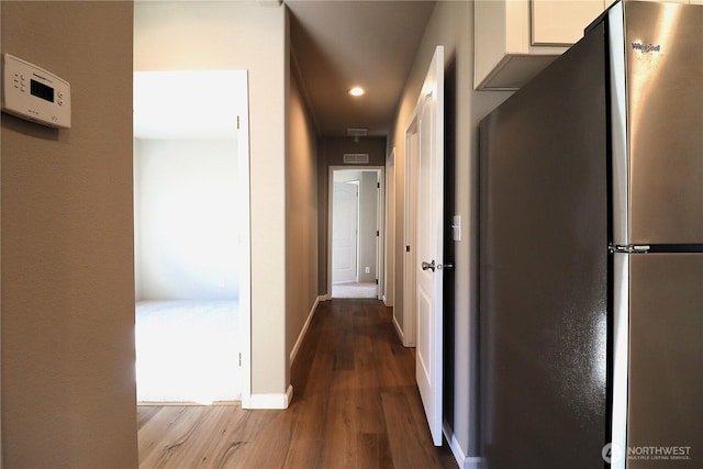 corridor with visible vents, wood finished floors, and baseboards