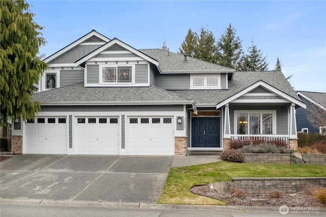 craftsman-style house featuring a garage, driveway, and roof with shingles