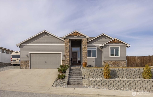 craftsman-style home featuring a garage, stone siding, concrete driveway, and fence