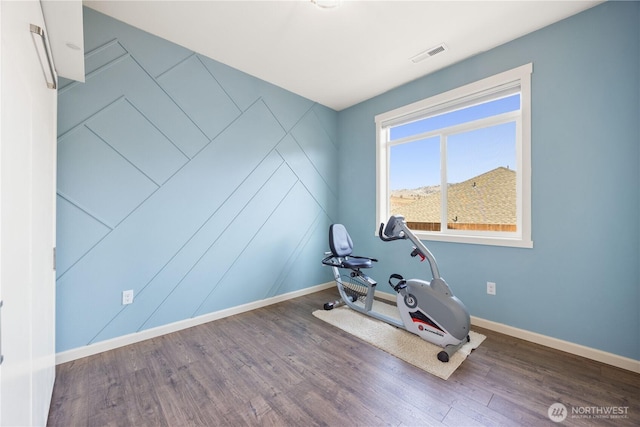 workout room featuring visible vents, baseboards, and wood finished floors