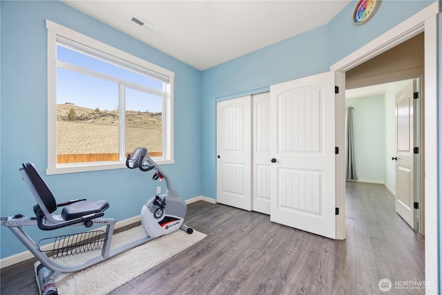 workout room featuring wood finished floors, visible vents, and baseboards