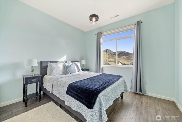 bedroom featuring visible vents, baseboards, and wood finished floors