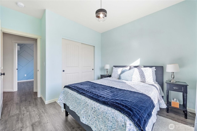 bedroom with wood finished floors, baseboards, and a closet