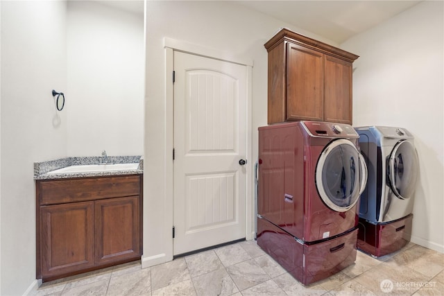 washroom with a sink, baseboards, cabinet space, and washer and dryer