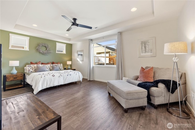 bedroom with recessed lighting, a tray ceiling, baseboards, and wood finished floors