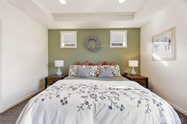 bedroom featuring baseboards, a raised ceiling, and wood finished floors