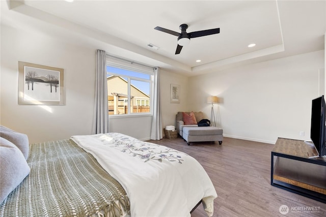 bedroom featuring visible vents, baseboards, a tray ceiling, recessed lighting, and wood finished floors