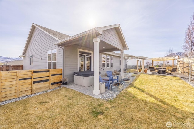 rear view of property with a patio area, a lawn, a hot tub, and a fenced backyard