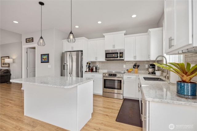 kitchen featuring backsplash, light stone countertops, light wood-style flooring, appliances with stainless steel finishes, and white cabinets