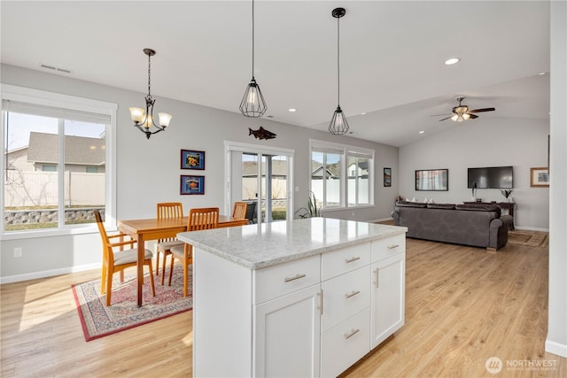 kitchen with decorative light fixtures, white cabinetry, light wood finished floors, baseboards, and vaulted ceiling