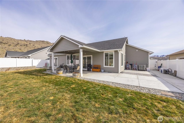 rear view of property featuring central AC unit, a patio area, a lawn, and a fenced backyard