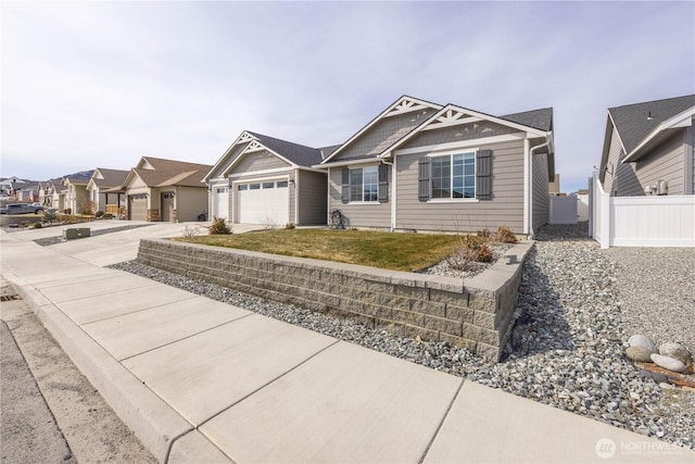 view of front facade with a front lawn, driveway, fence, a residential view, and a garage