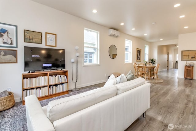 living room with recessed lighting, wood finished floors, baseboards, and a wall mounted AC