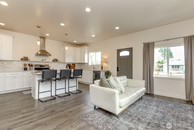 living room with recessed lighting, light wood-type flooring, and baseboards