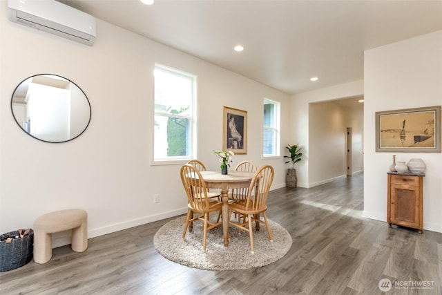 dining area with a wall mounted air conditioner, baseboards, wood finished floors, and recessed lighting