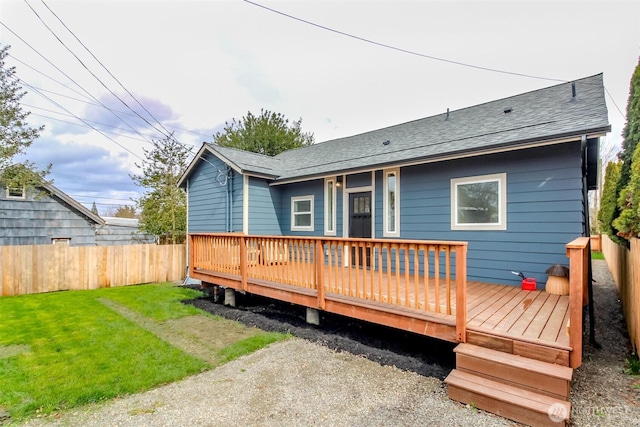 back of house featuring a deck, roof with shingles, a yard, and fence