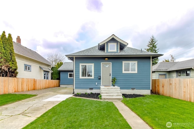 bungalow with a shingled roof, a front yard, and fence