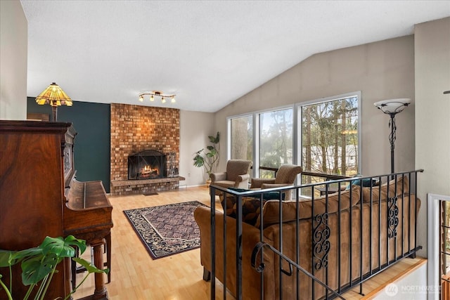 living room with lofted ceiling, a brick fireplace, and wood finished floors