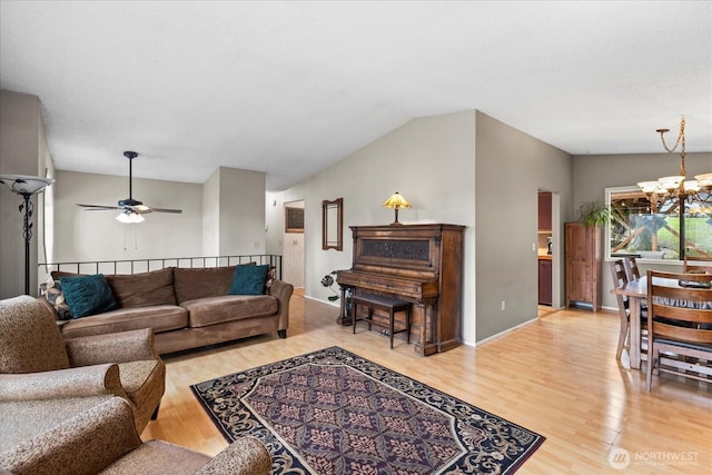 living area with baseboards, ceiling fan with notable chandelier, vaulted ceiling, and light wood finished floors