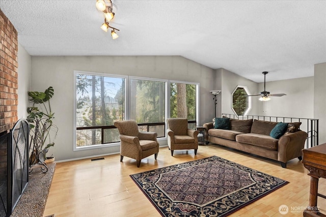 living room with visible vents, plenty of natural light, a brick fireplace, and wood finished floors