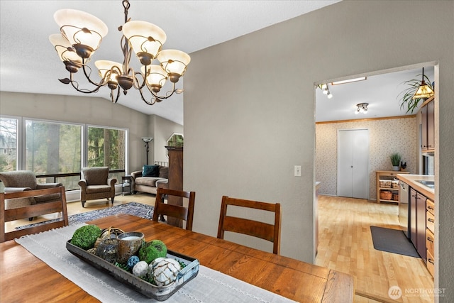 dining room with light wood finished floors, a notable chandelier, lofted ceiling, and wallpapered walls