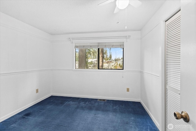 spare room with baseboards, a textured ceiling, ceiling fan, and dark colored carpet