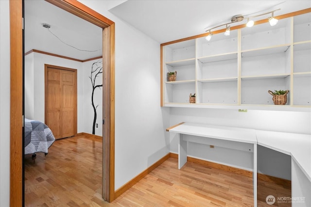 office area featuring light wood finished floors, crown molding, and baseboards