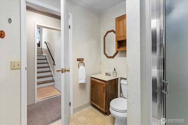 full bathroom featuring an enclosed shower, toilet, wallpapered walls, and vanity