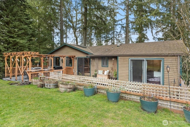 back of house featuring a lawn, a pergola, roof with shingles, and a wooden deck