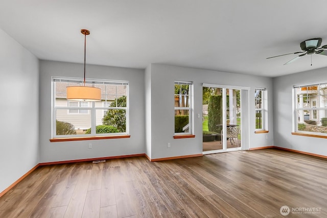 unfurnished living room with ceiling fan, baseboards, and wood finished floors