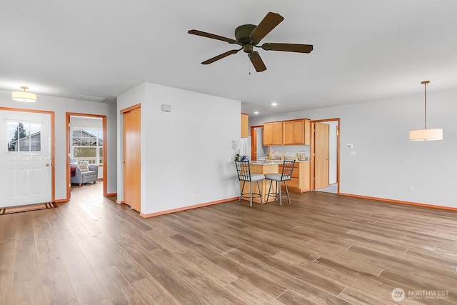 unfurnished living room featuring recessed lighting, ceiling fan, baseboards, and wood finished floors