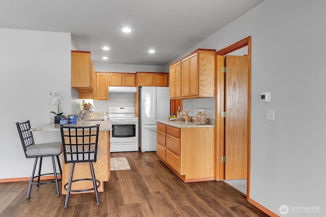 kitchen featuring white appliances, a peninsula, recessed lighting, dark wood-style flooring, and under cabinet range hood