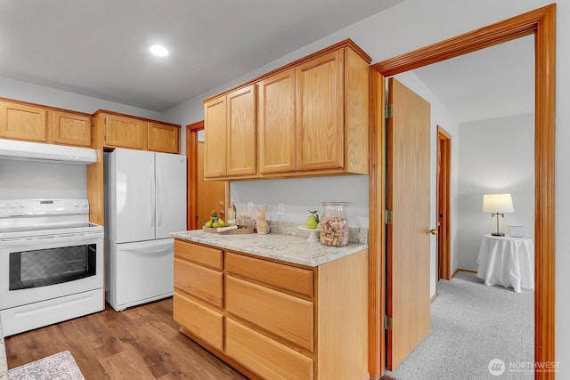 kitchen featuring white appliances, wood finished floors, light stone countertops, and under cabinet range hood