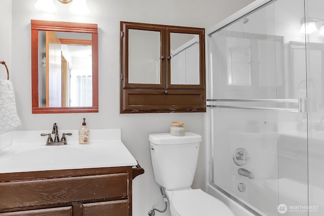 bathroom with toilet, vanity, and bath / shower combo with glass door