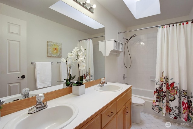 bathroom featuring a sink, toilet, a skylight, and double vanity