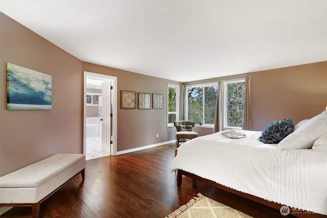 bedroom with connected bathroom, baseboards, and wood finished floors