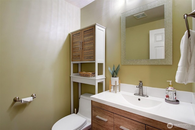 half bathroom featuring visible vents, toilet, and vanity