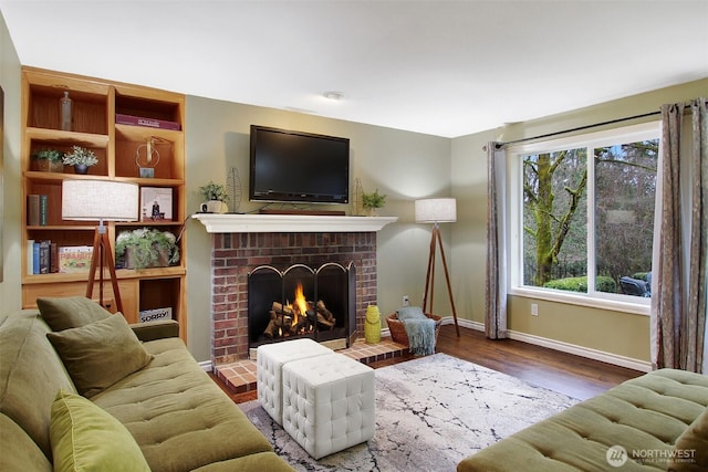 living room featuring a brick fireplace, wood finished floors, and baseboards